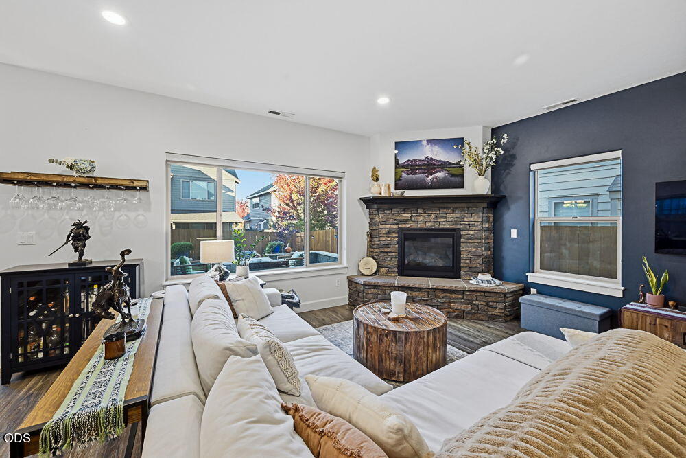 Living room with a white sectional, stone fireplace, and large windows overlooking autumn foliage.