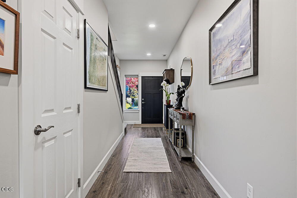 Entry hallway with dark wood floors, a staircase, console table, and dark front door.