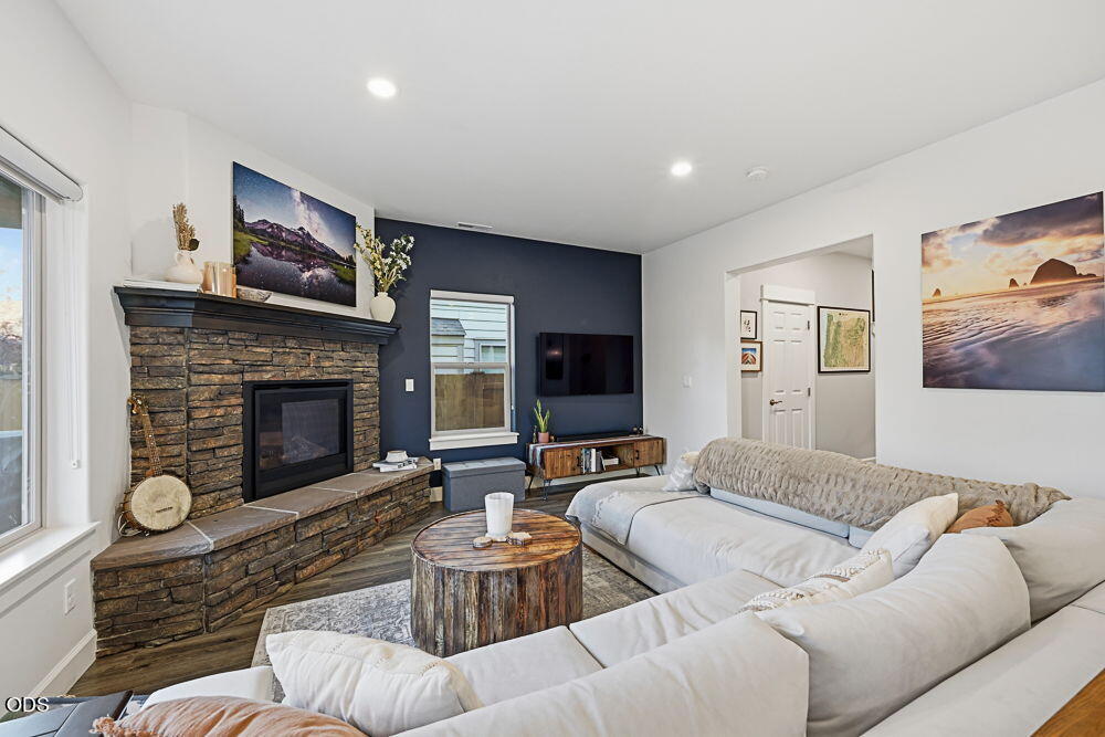 Living room with a stone fireplace, dark blue accent wall, and large white sectional sofa.