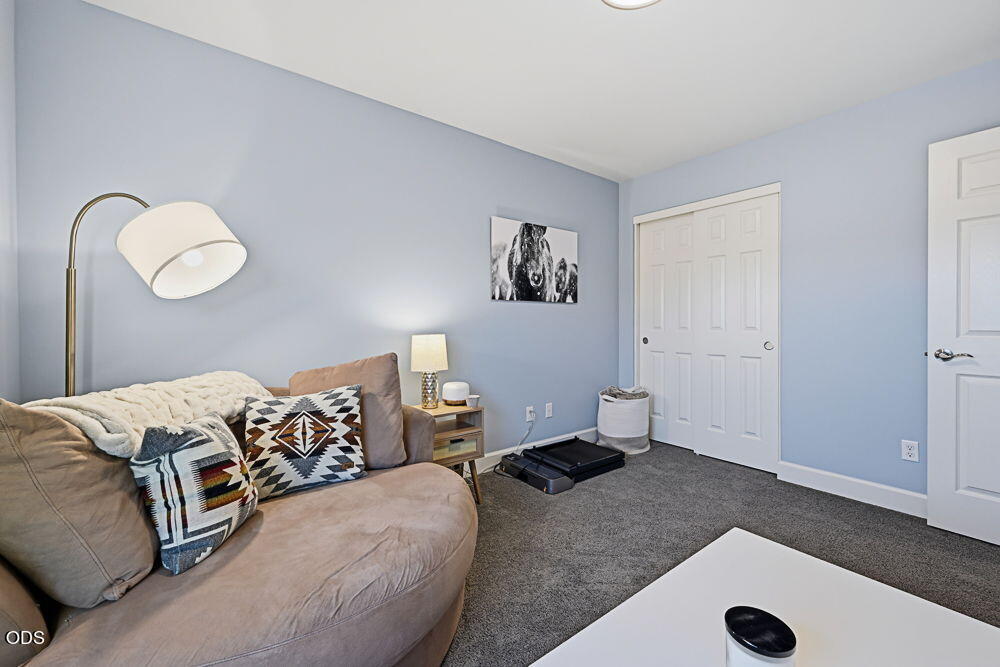Living room with a beige sectional, patterned pillows, blue walls, and white closet doors.