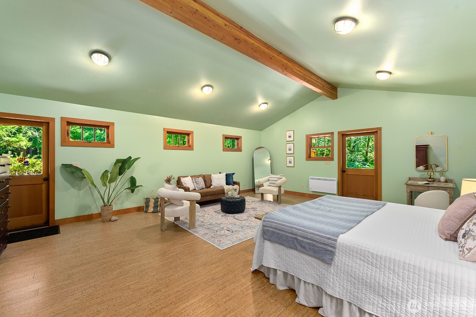 Bedroom with a vaulted ceiling, exposed wood beam, and a small sitting area.