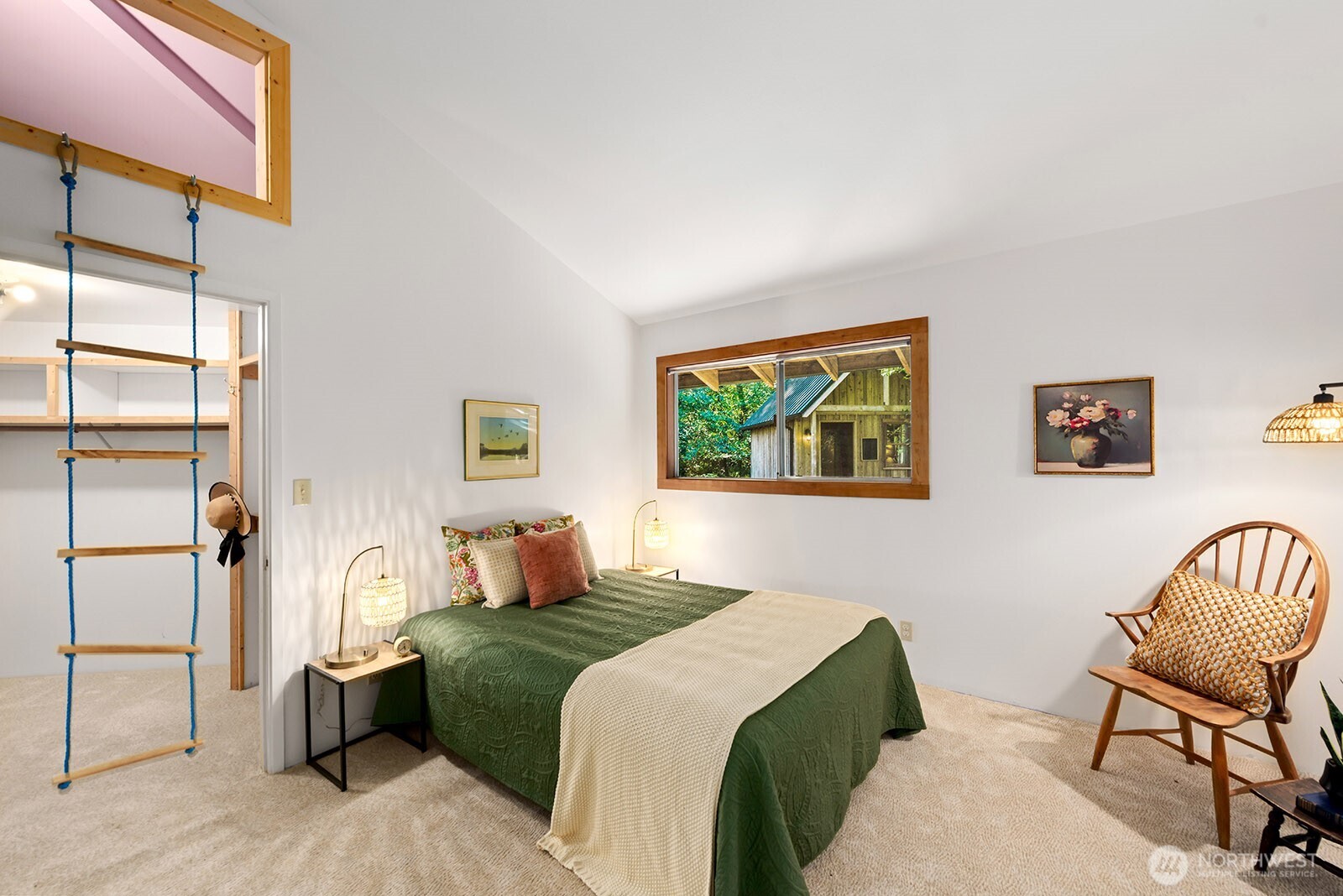 Bedroom with a green-covered bed and wooden rope ladder leading to a loft.