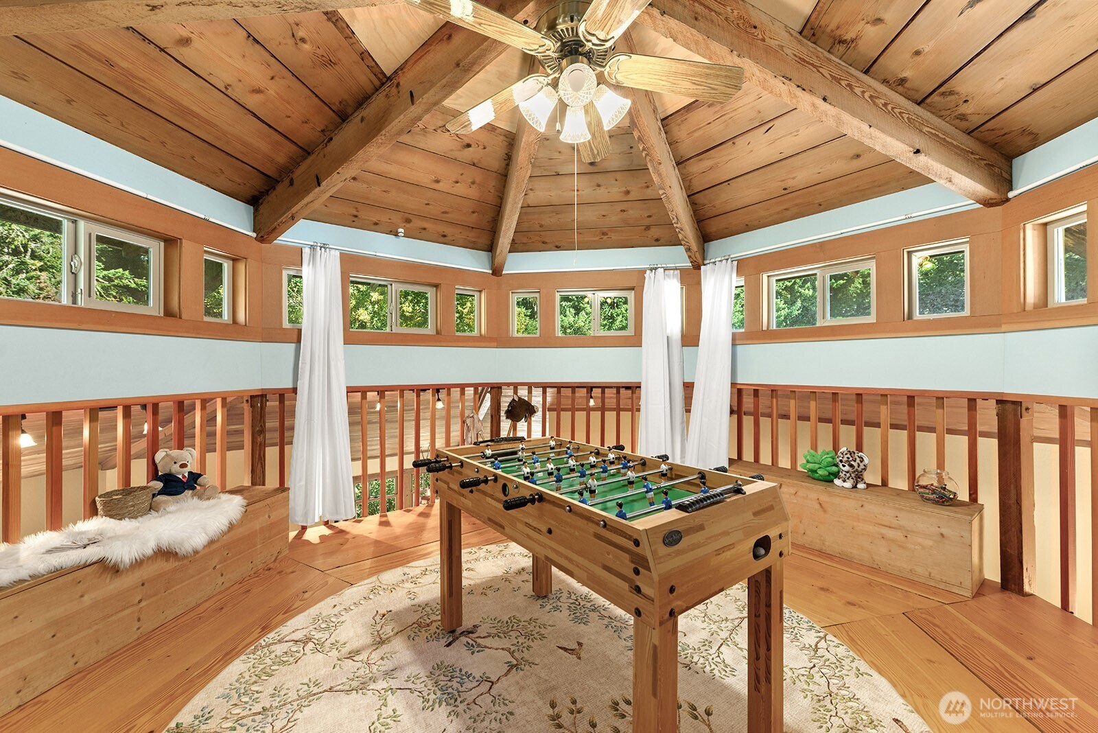 Game room with foosball table, built-in window benches, and a high exposed timber ceiling.