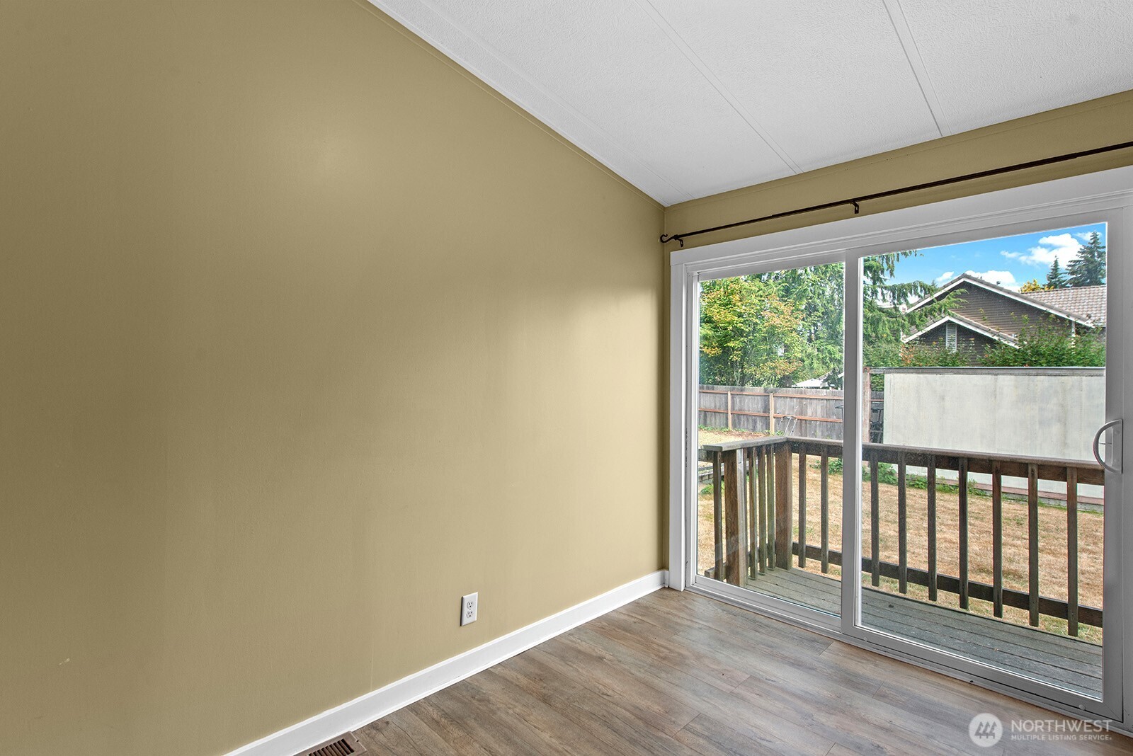 Empty room with wood-look flooring and sliding glass doors opening to a deck.