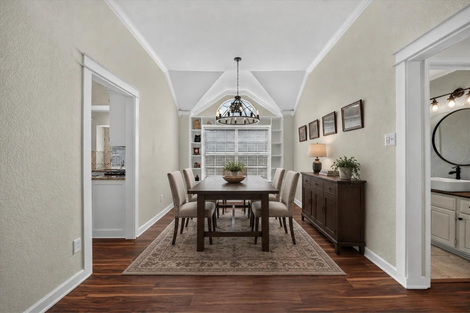 Dining room with vaulted ceiling, dark wood table, built-in window shelves, and patterned rug.