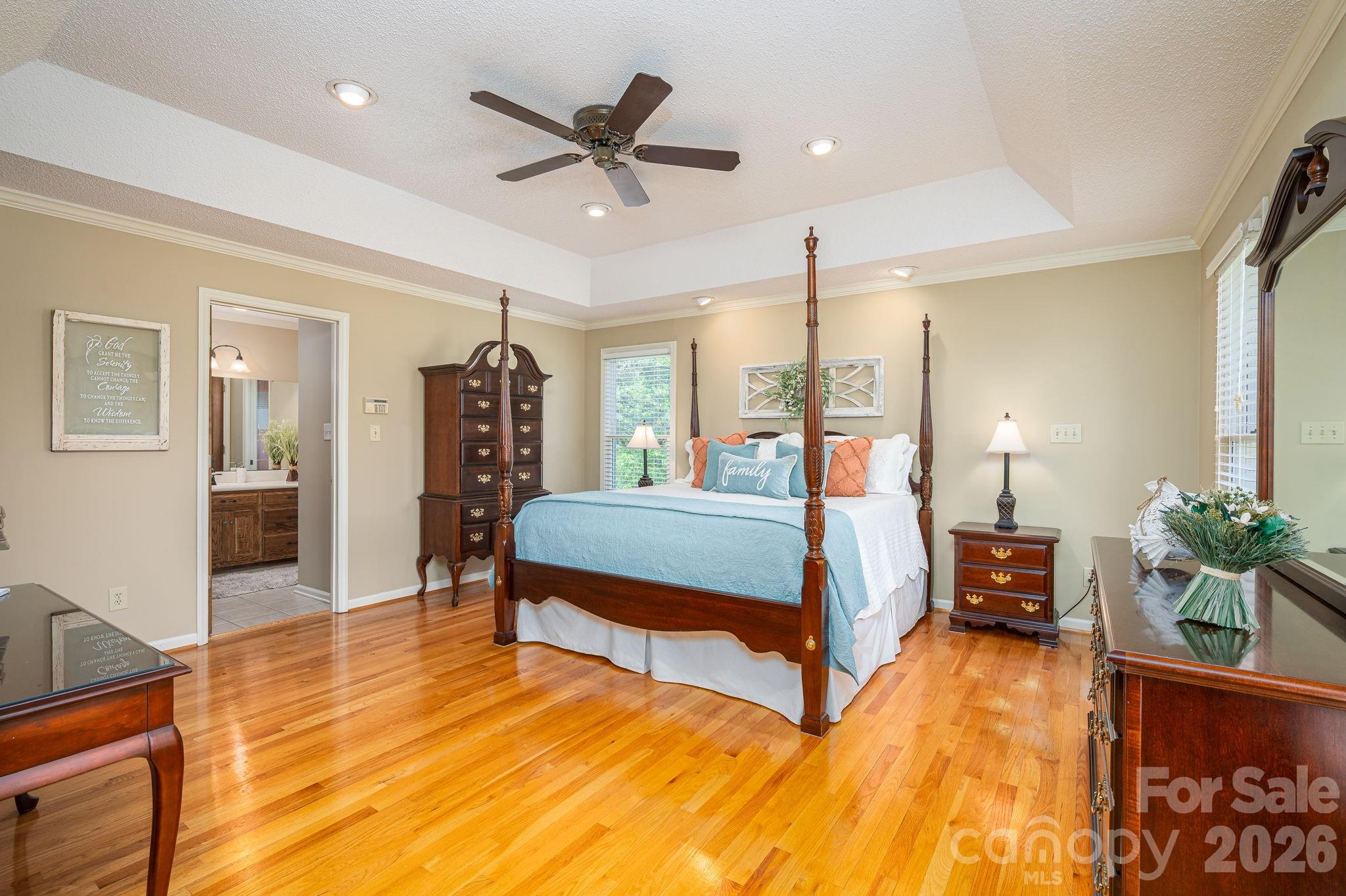 Bedroom with a dark wood four-poster bed, pale blue bedding, and polished hardwood floors.