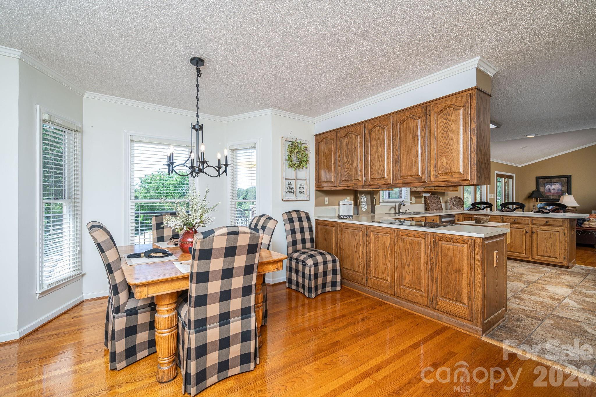 Kitchen and dining area with wood cabinetry, a central island, and plaid dining chairs.