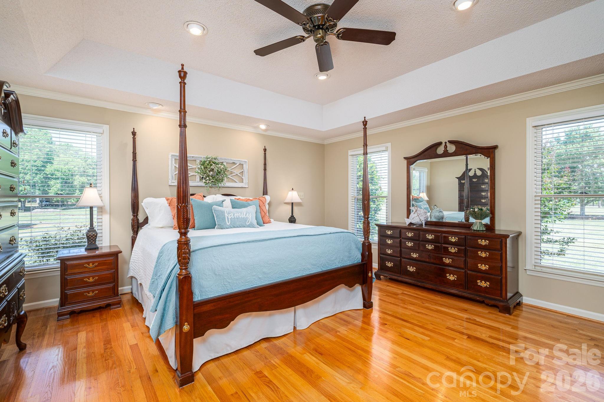 Furnished bedroom with a dark wood four-poster bed, blue bedding, and hardwood floors.