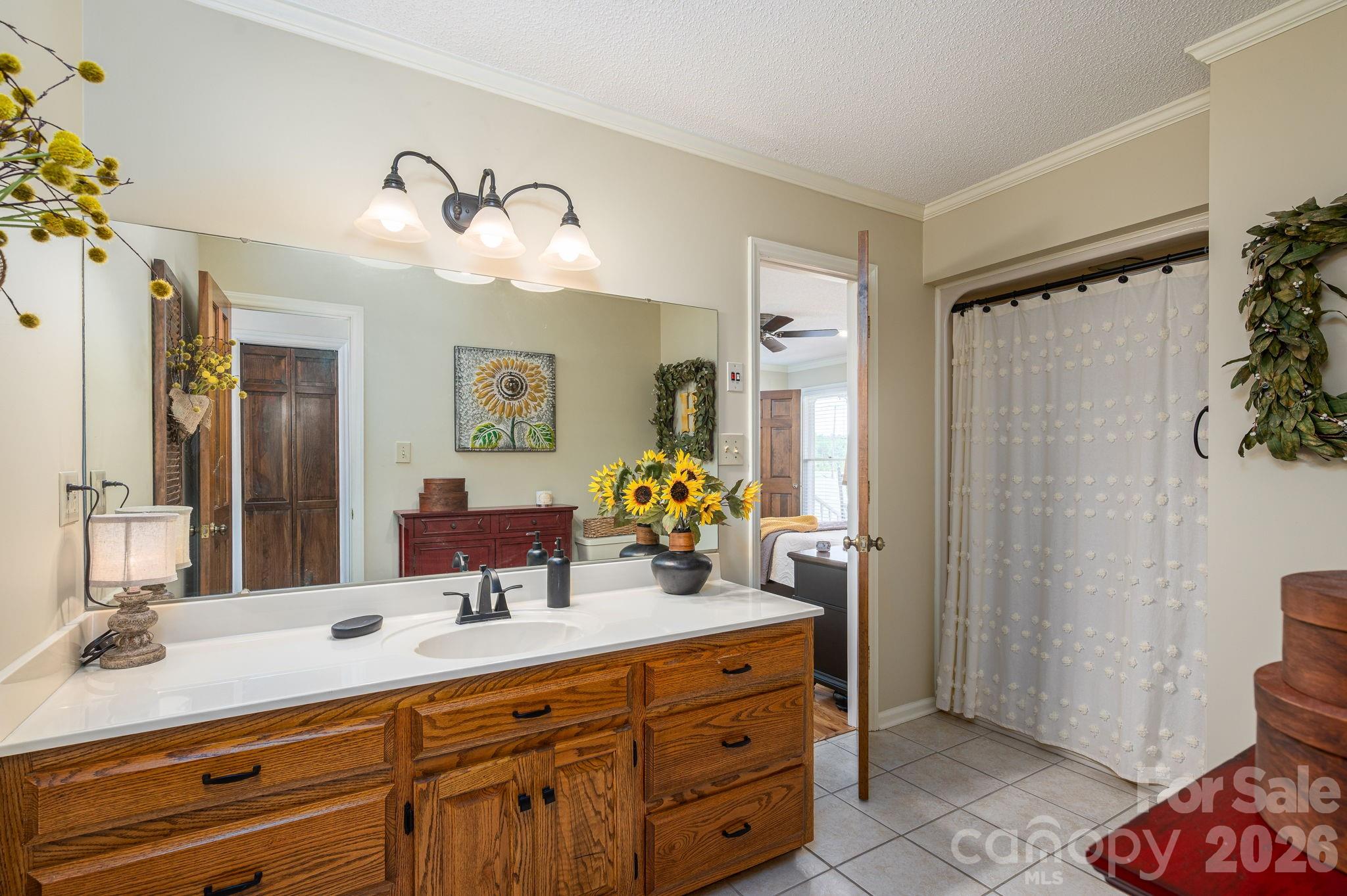 Bathroom with a wide oak vanity, white countertop, large mirror, and white shower curtain.