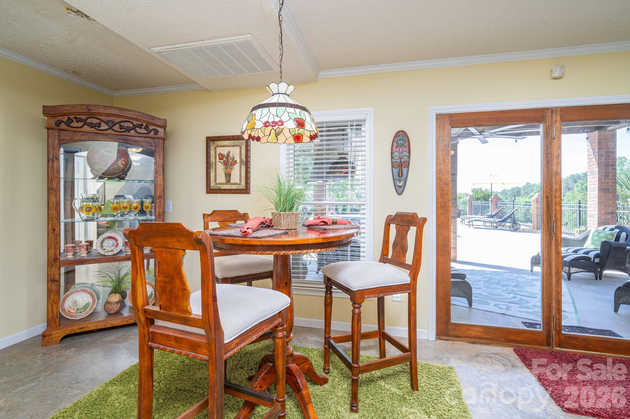 Dining area with a round wooden table and sliding doors opening to a covered patio.