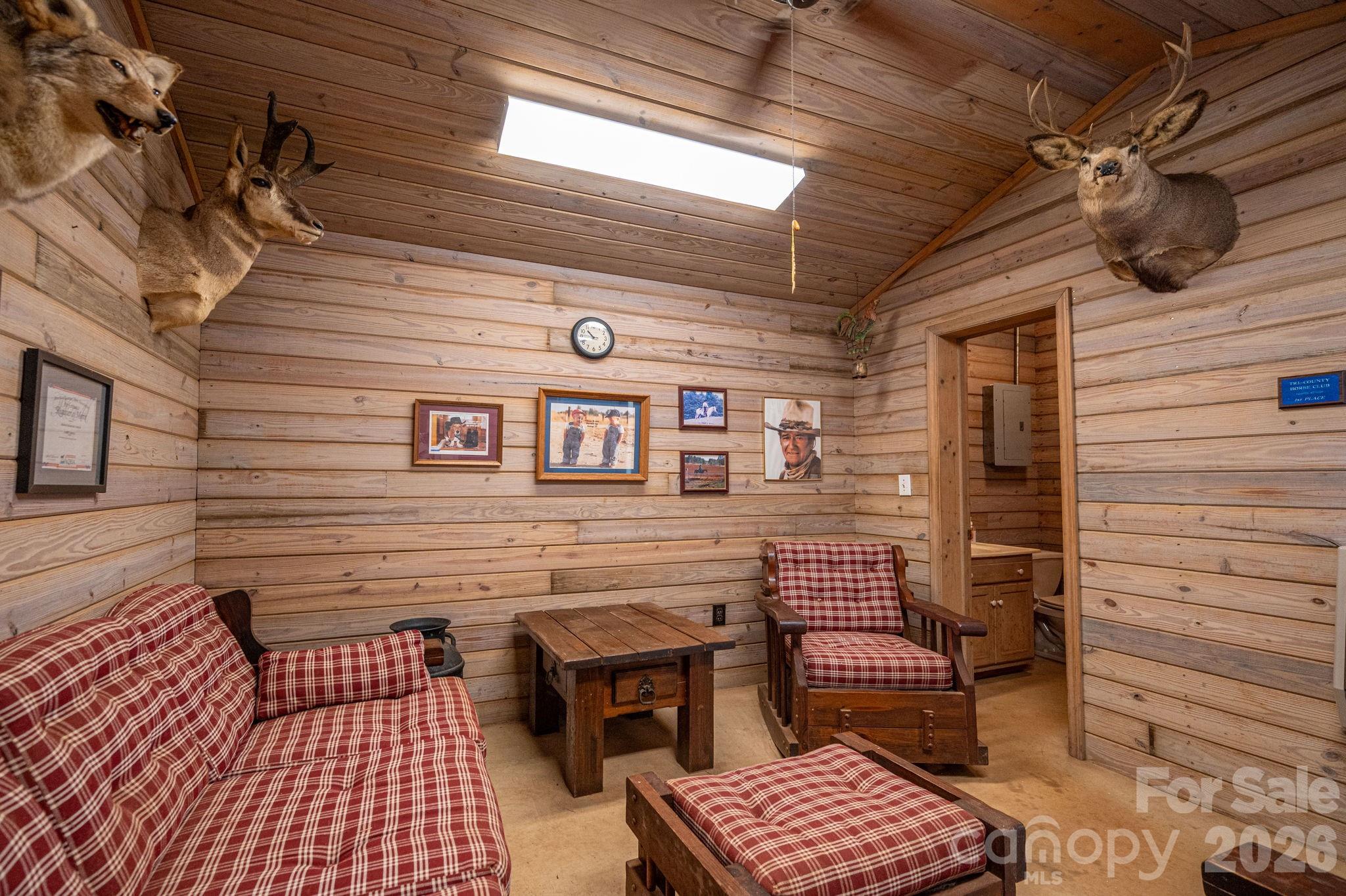 Rustic wood-paneled lounge with red plaid seating, a wooden coffee table, and mounted taxidermy.
