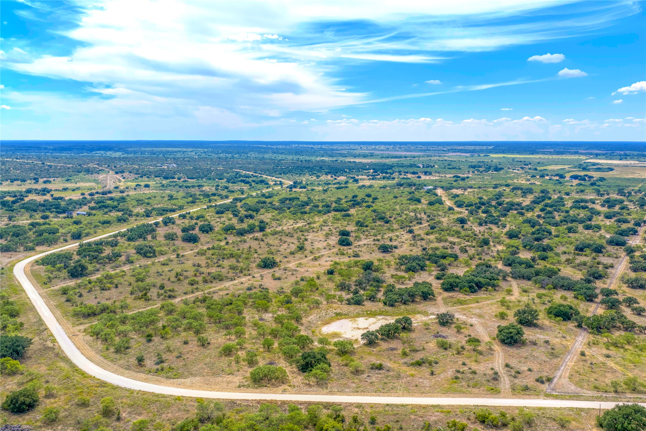 Aerial view of scrub-covered acreage crossed by a winding rural road.