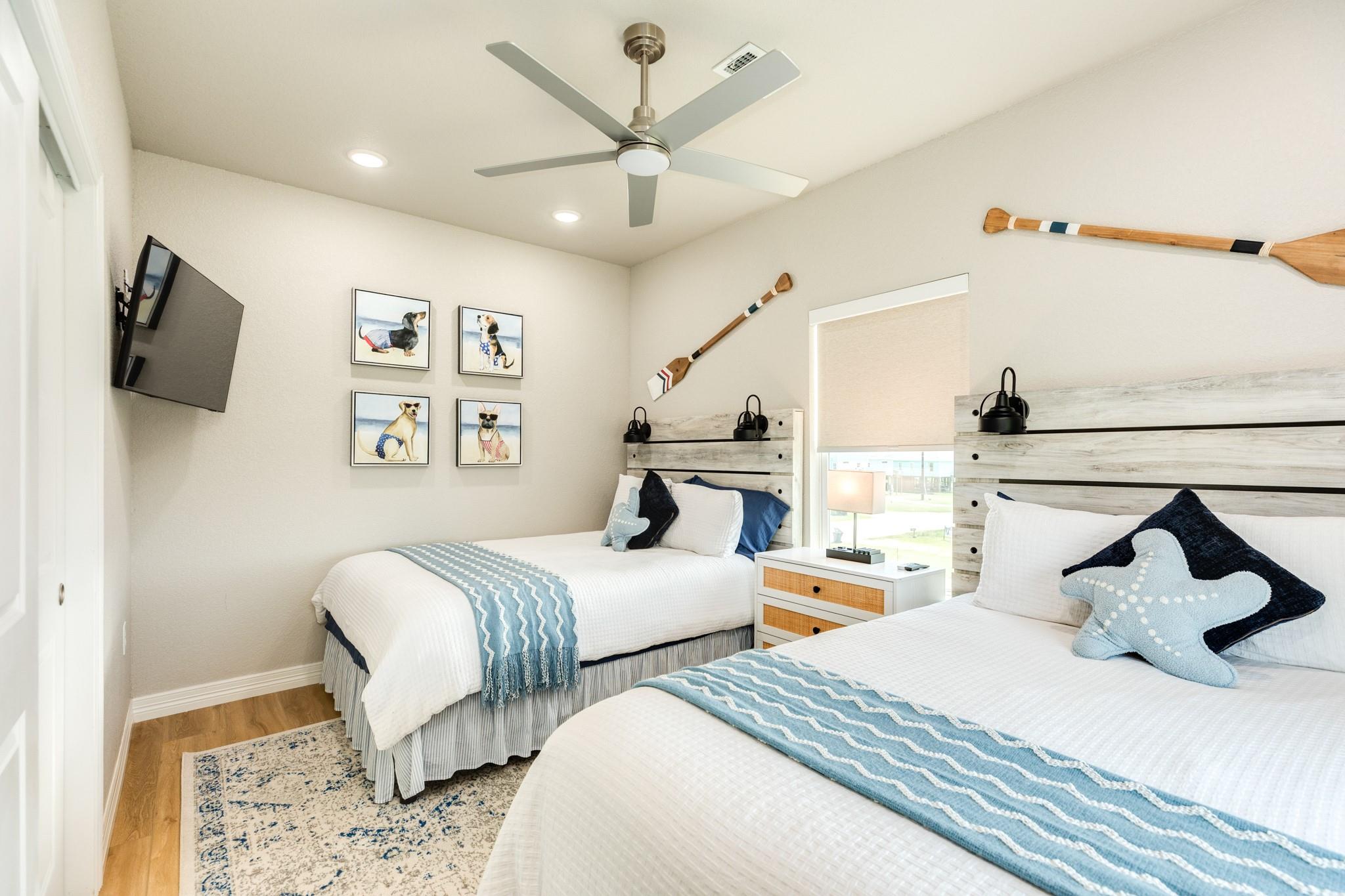 Bedroom with two beds, blue accents, rustic wood headboards, and nautical decor.