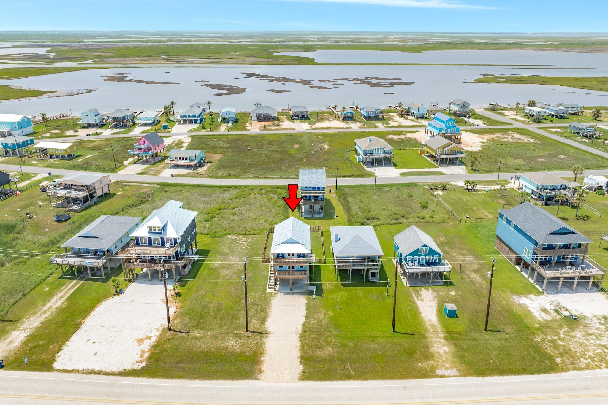Aerial view of the home marked by a red arrow beside coastal marshes.