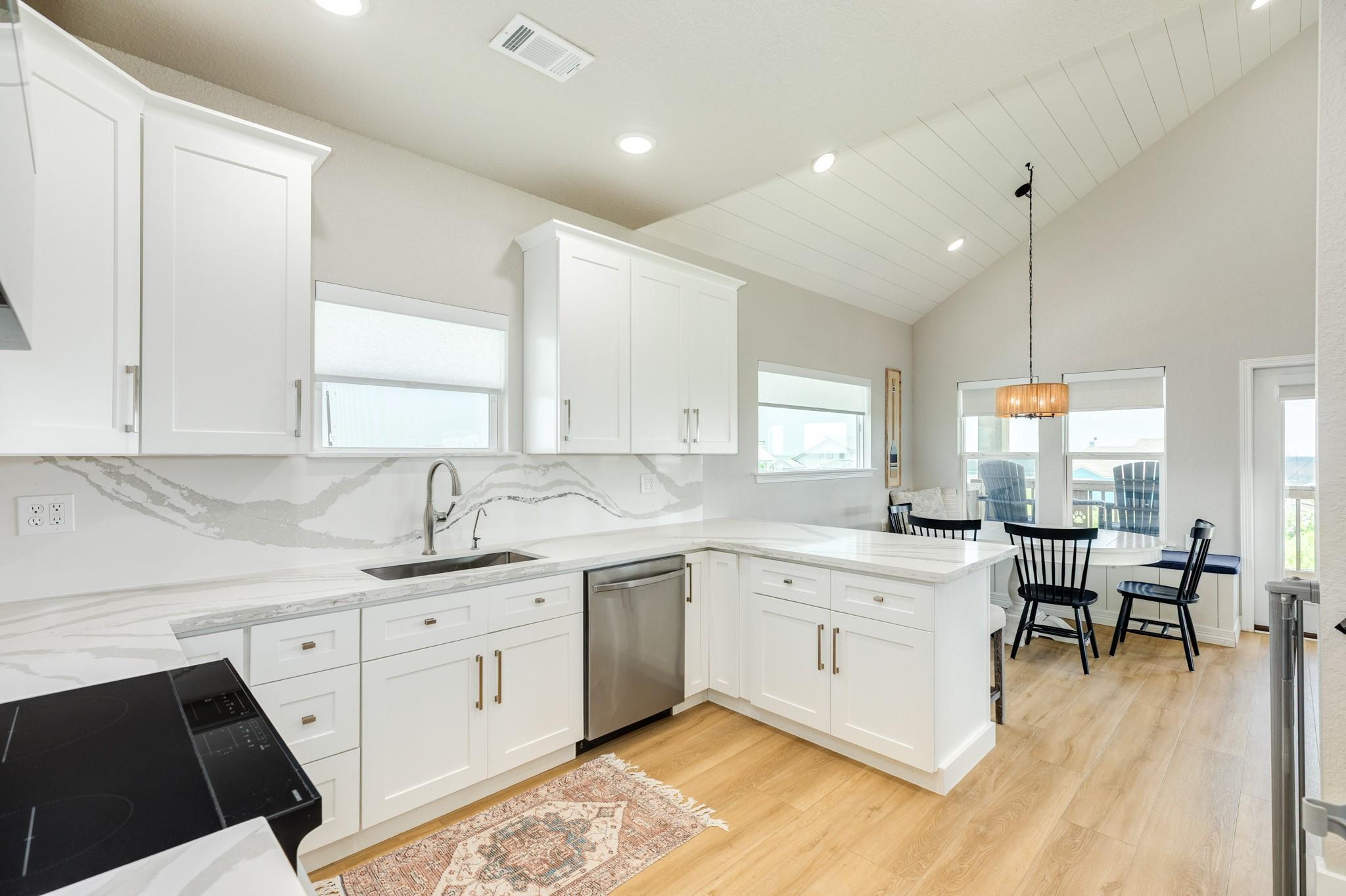 Bright white kitchen with veined stone backsplash, stainless steel appliances, and an adjoining dining nook.