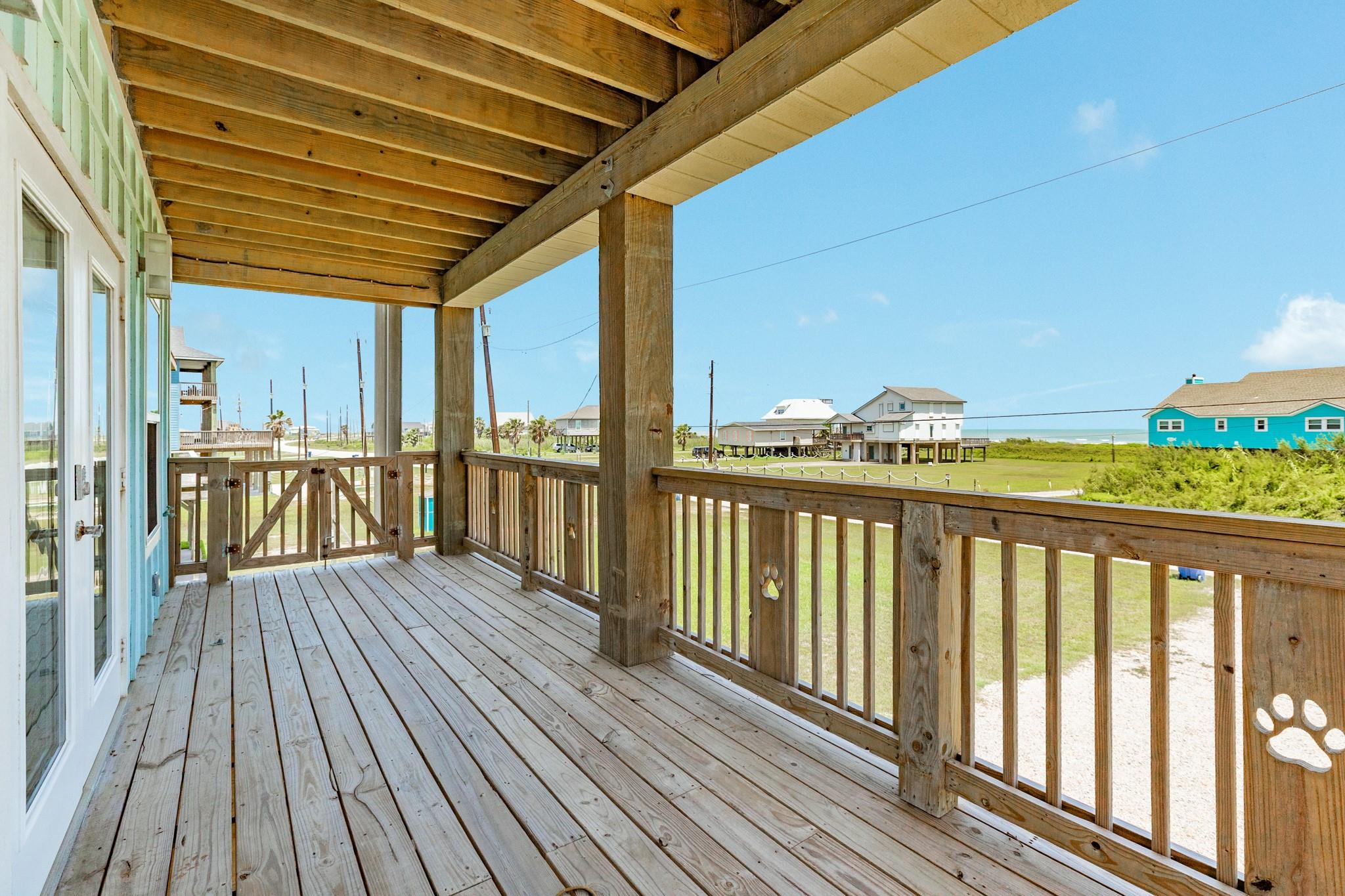 Covered wooden porch overlooking coastal homes and a strip of ocean