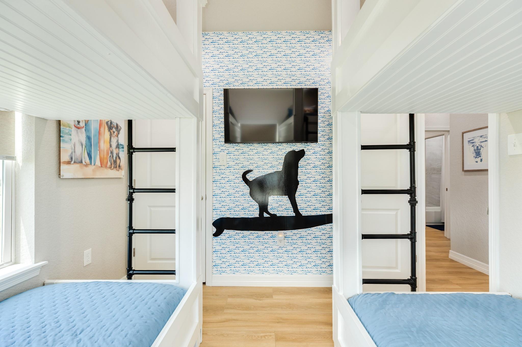 Bedroom with twin built-in loft beds, black pipe ladders, and wave-patterned wallpaper featuring a dog silhouette.