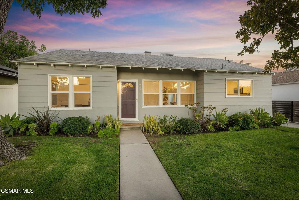 Gray single-story house with a central walkway and landscaped front lawn at dusk.