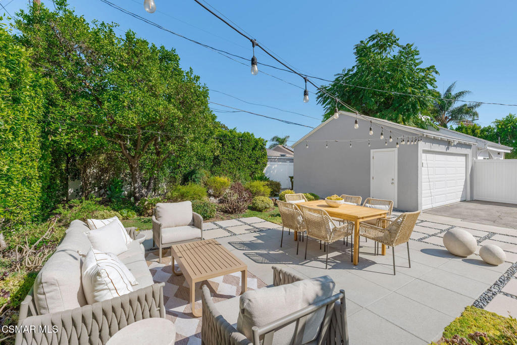 Outdoor patio with lounge seating and a dining table beside a detached garage.