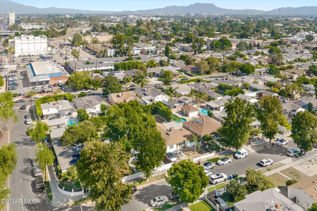 Aerial view of a residential neighborhood with backyard pools and distant mountains.