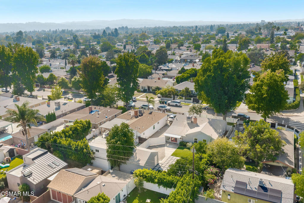 Aerial view of a tree-lined residential neighborhood with distant hills.