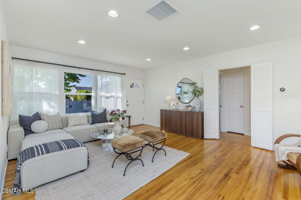 Staged living room with a gray sectional, marble coffee tables, and warm hardwood floors.