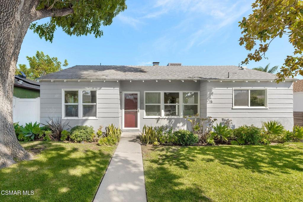 Single-story gray house with a red front door, front lawn, and mature trees.
