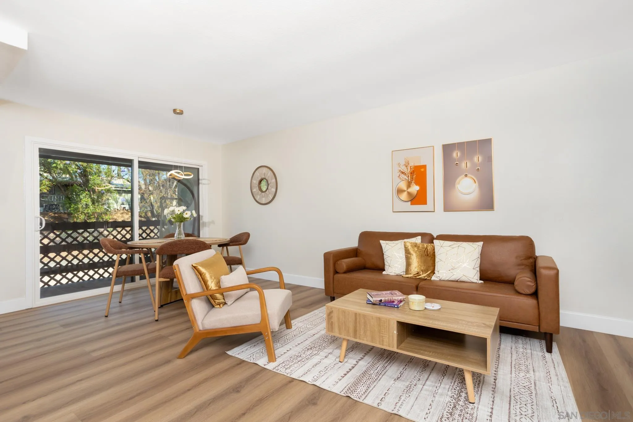 Staged living room with a brown sofa, wood coffee table, and dining area by sliding glass doors.