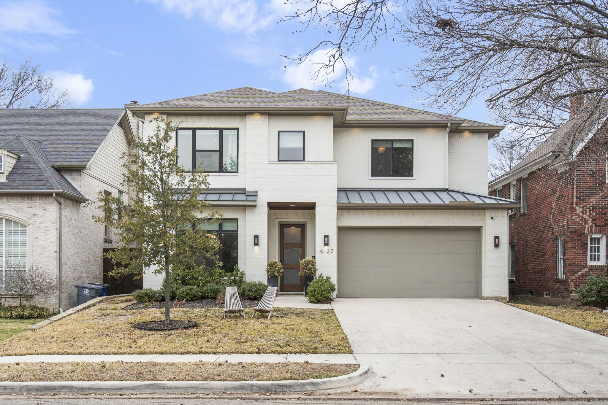 Two-story white brick home with a double garage, wide driveway, and front lawn.