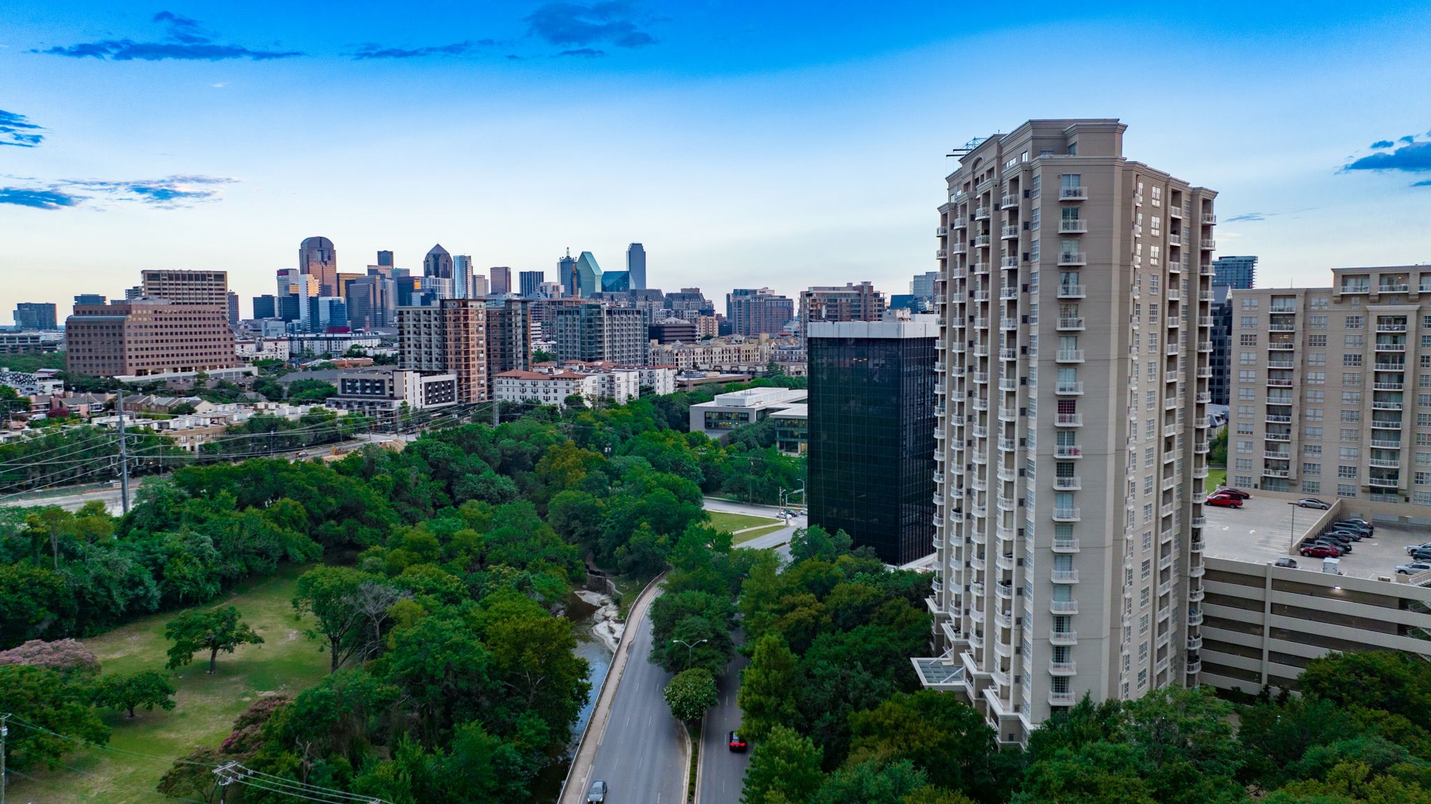 High-rise condominium overlooking a tree-lined road and the downtown Dallas skyline.