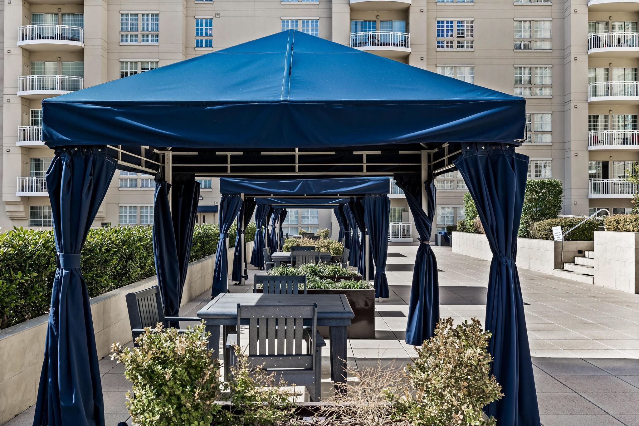 High-rise courtyard with navy cabanas, outdoor dining tables, and planters.