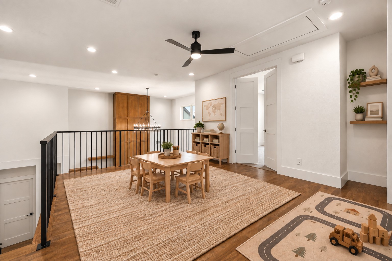 Upstairs dining area with a wooden table, black railing, and children's play rug.