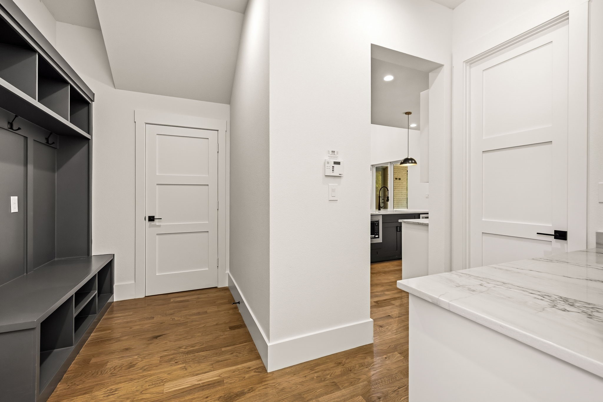 Entry hall with built-in dark cubbies and bench beside a kitchen island.