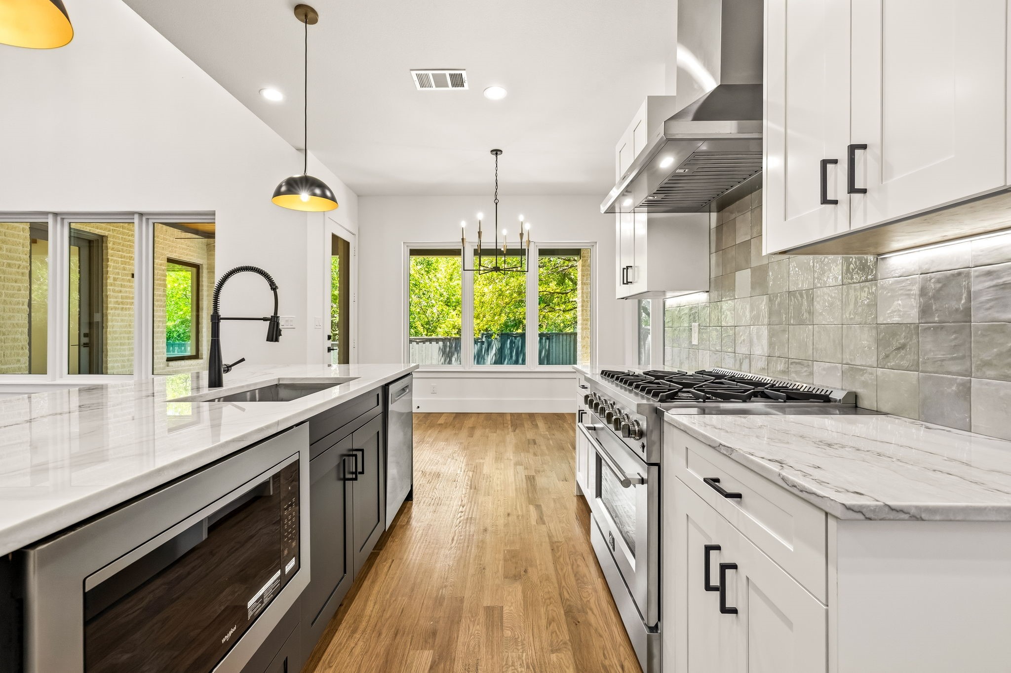 Kitchen with white cabinets, marble-look counters, a large island, and a stainless steel range.