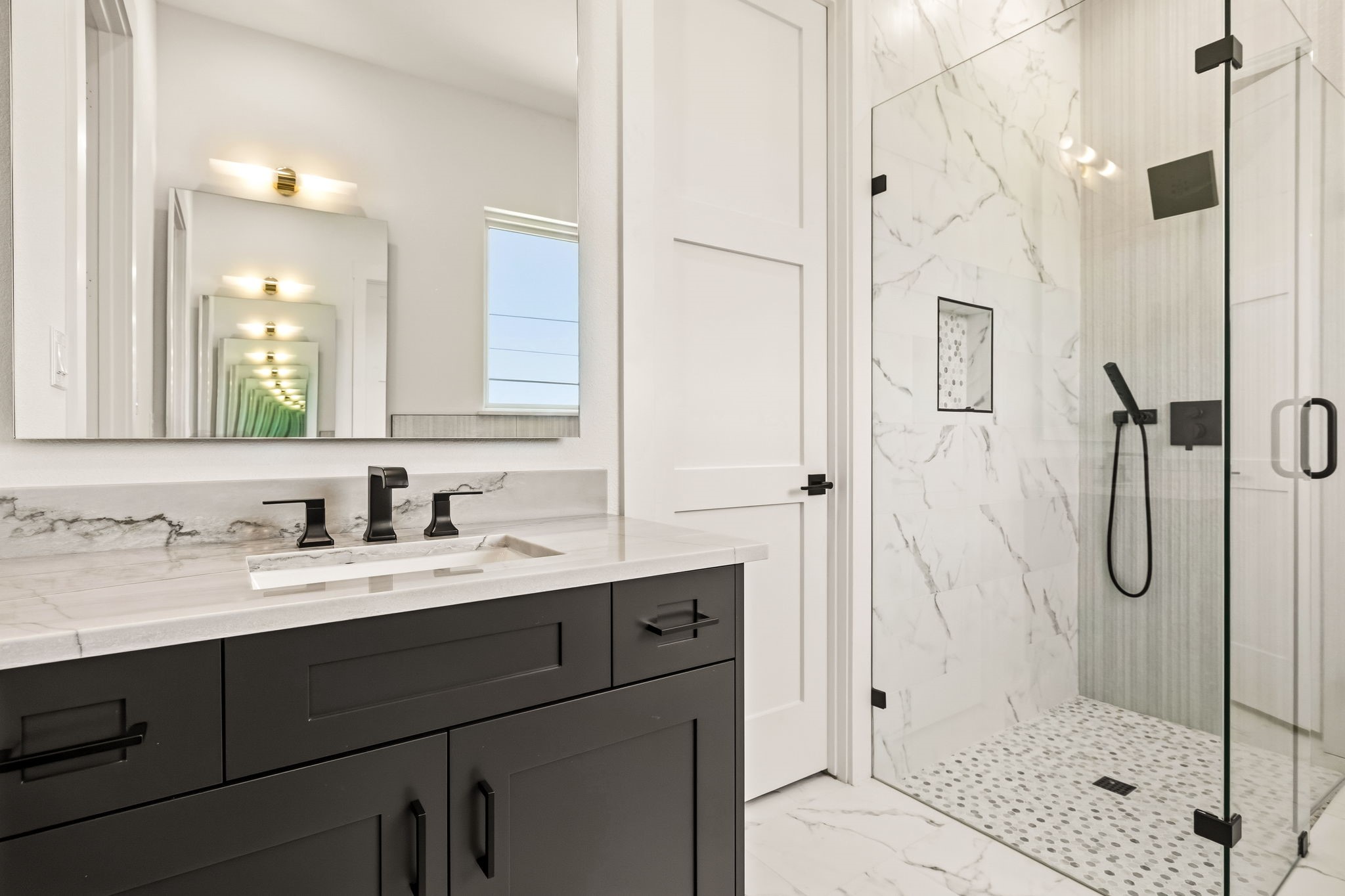 Modern bathroom with a dark vanity and marble walk-in shower.