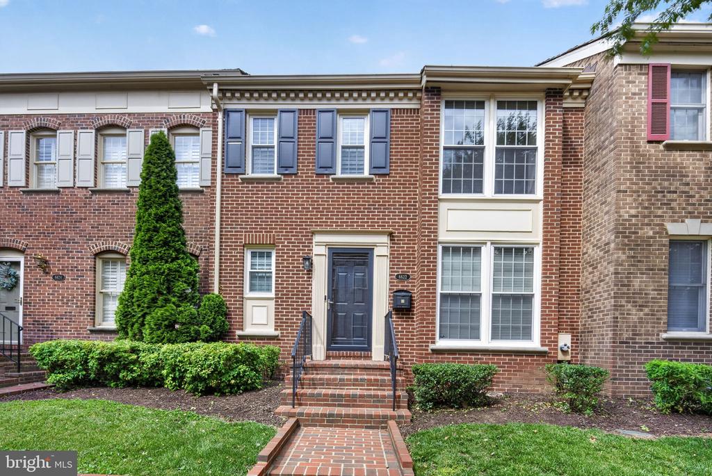 Red-brick townhouse with blue shutters, a blue front door, and brick front steps.