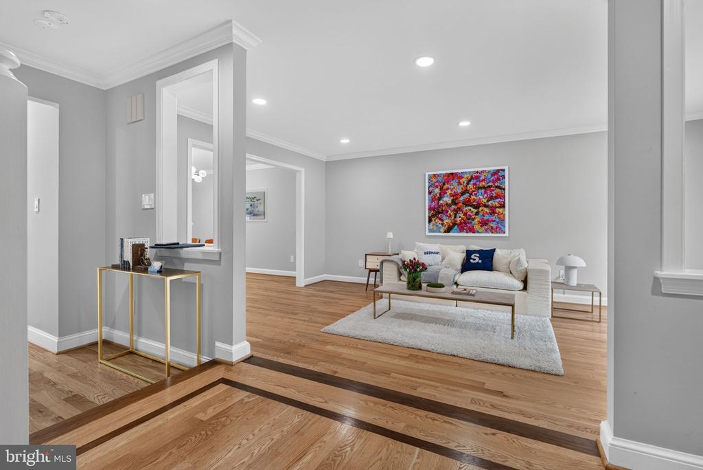 Staged living room with a white sofa, colorful floral artwork, and hardwood floors.