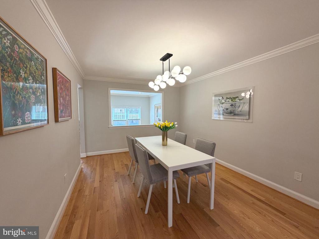 Dining room with a white table, gray chairs, hardwood floors, and a modern globe chandelier.
