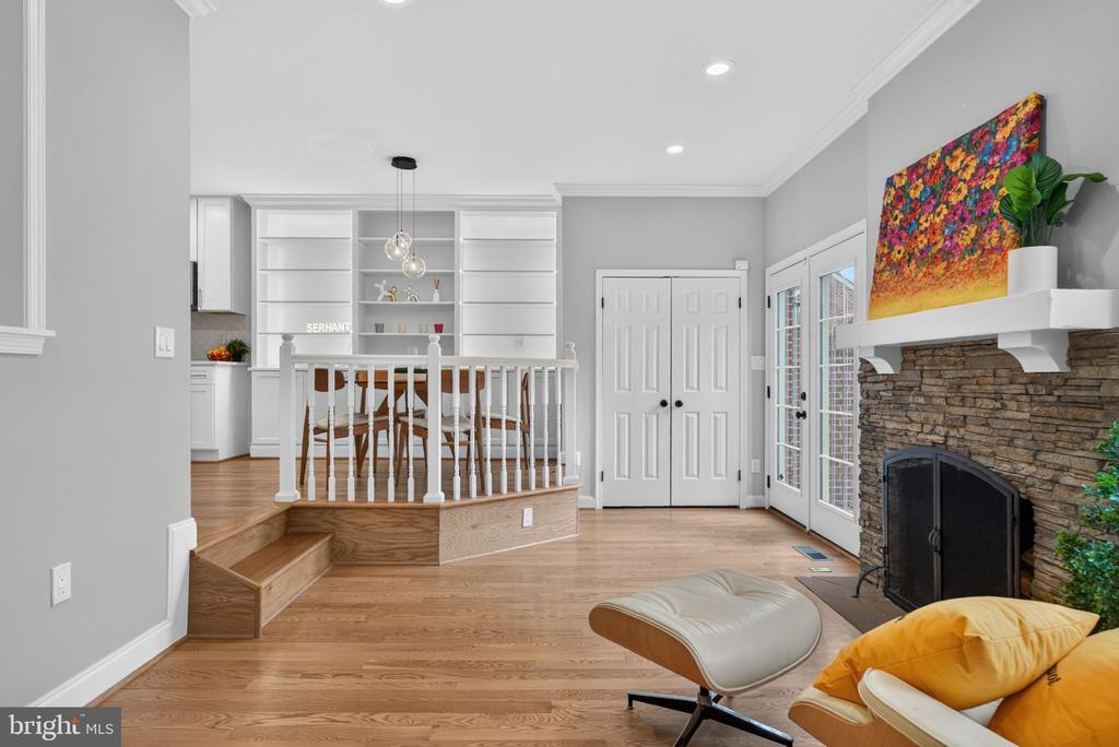 Living room with a stone fireplace, French doors, and a raised dining area with built-in shelves.