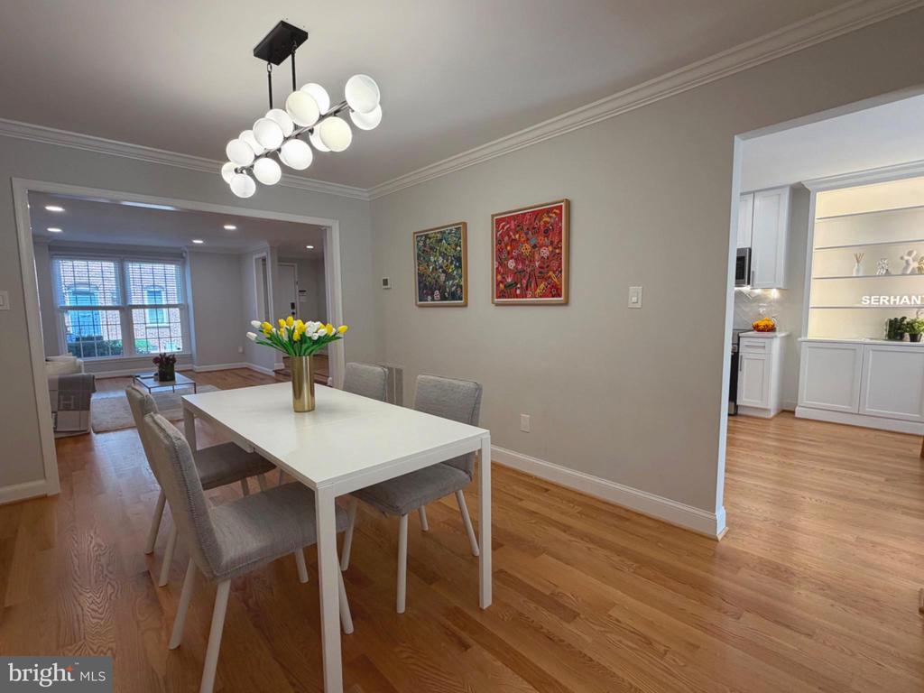 Dining room with a white table, globe chandelier, hardwood floors, and adjoining living room and kitchen.