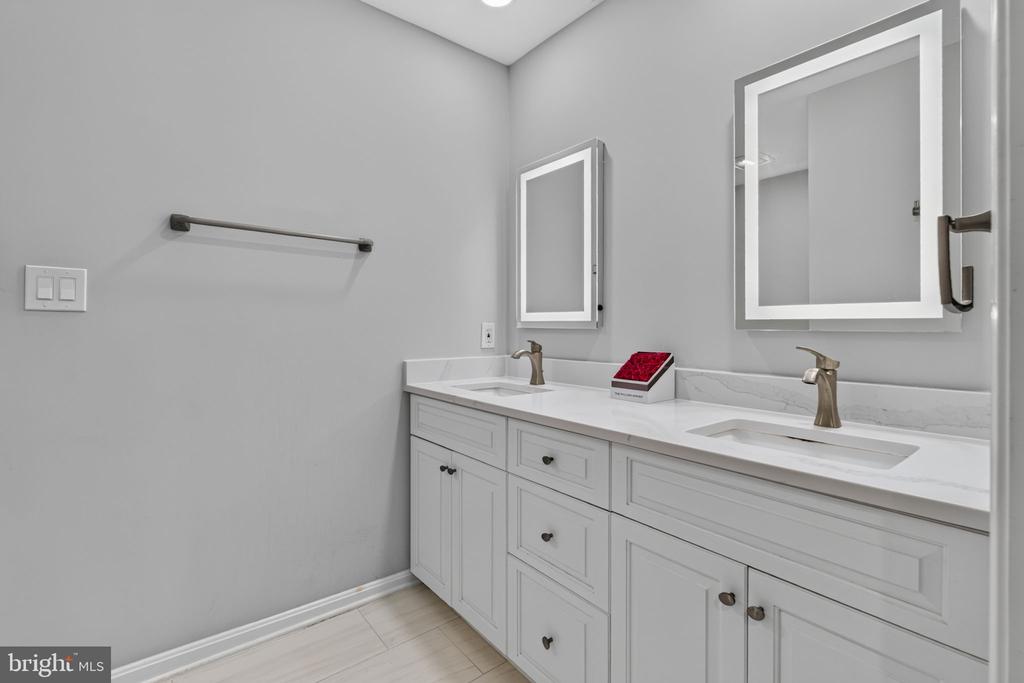 Bathroom with a long white double vanity, two framed mirrors, and bronze-tone faucets.