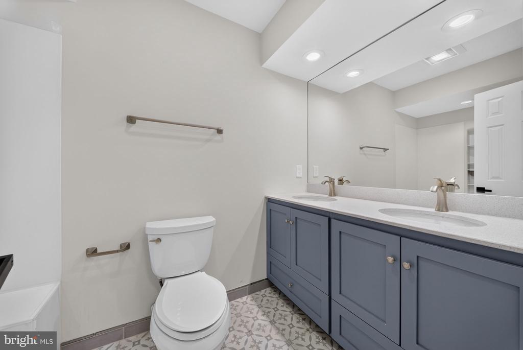 Bathroom with a blue-gray double vanity, large mirror, and patterned tile floor.