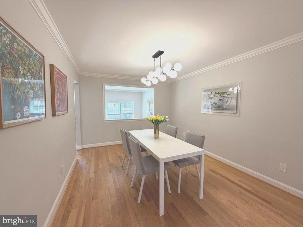 Furnished dining room with a white table, gray chairs, hardwood floors, and a modern globe chandelier.