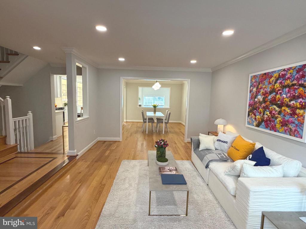Living and dining room with hardwood floors, white sectional sofa, and colorful floral wall art.