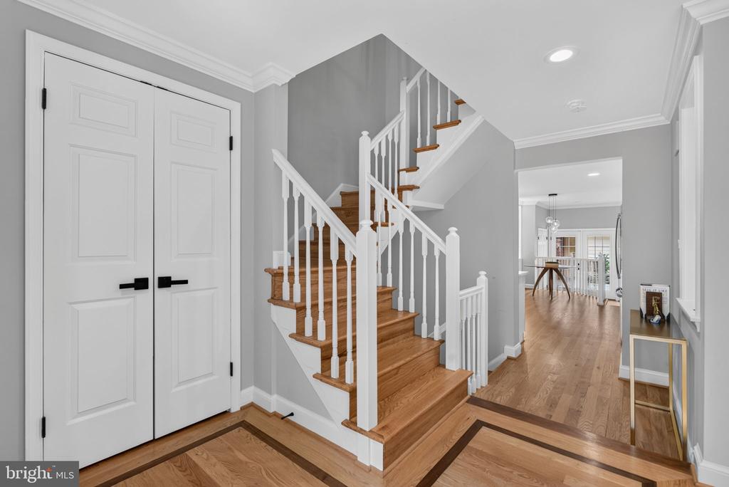Foyer with a hardwood staircase, white double doors, and hardwood floors.