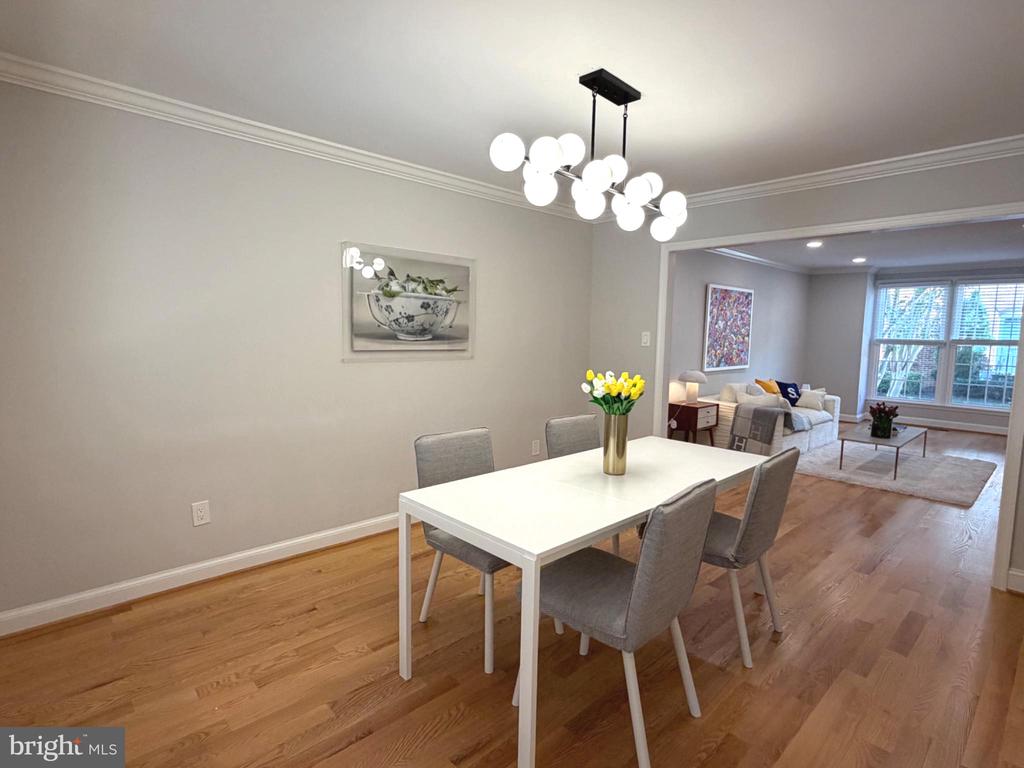 Dining room with a white table and globe chandelier, opening into a bright living room.