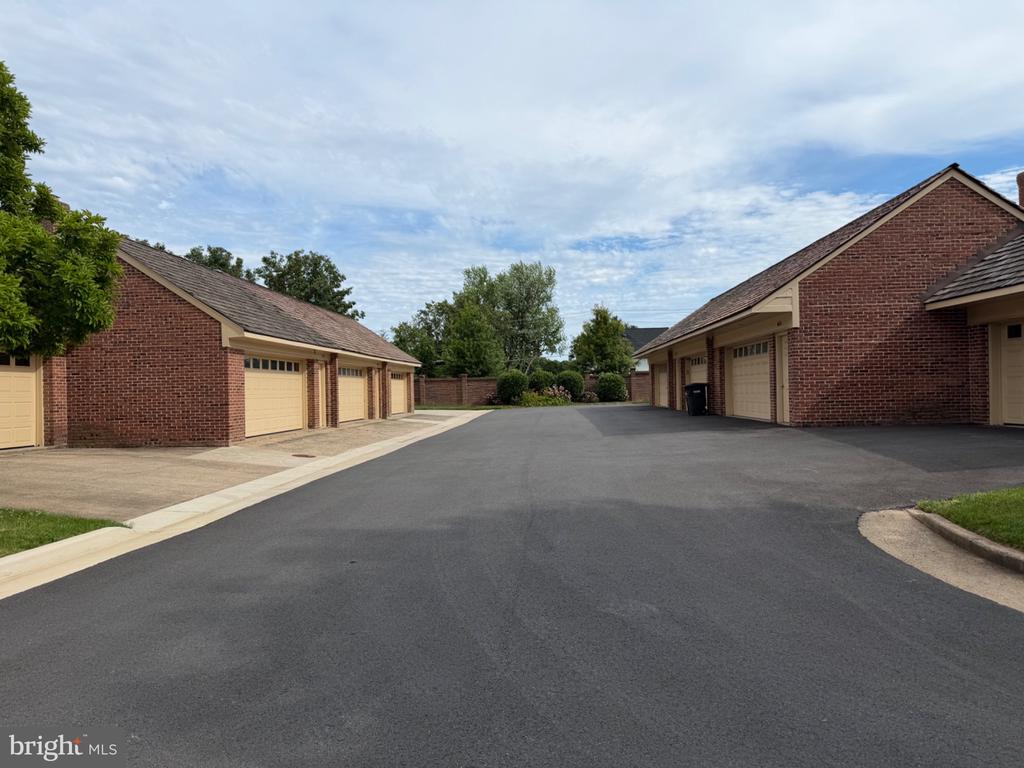 Paved drive between red-brick garages with beige doors.