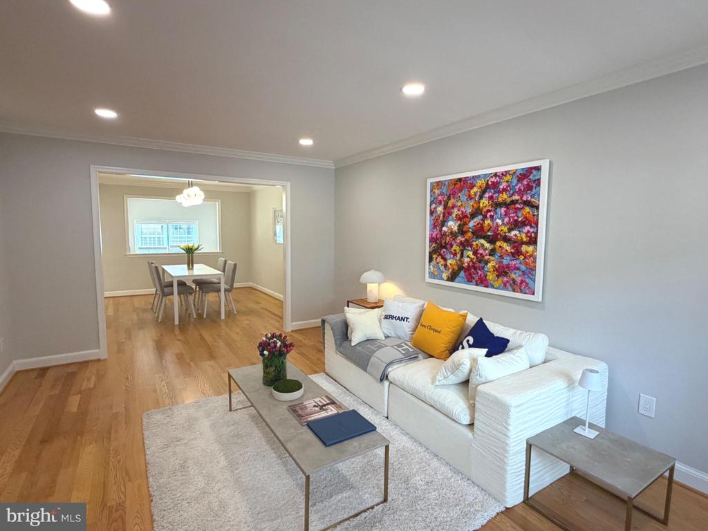 Living room with a white sectional, colorful wall art, and an open doorway to the dining room.