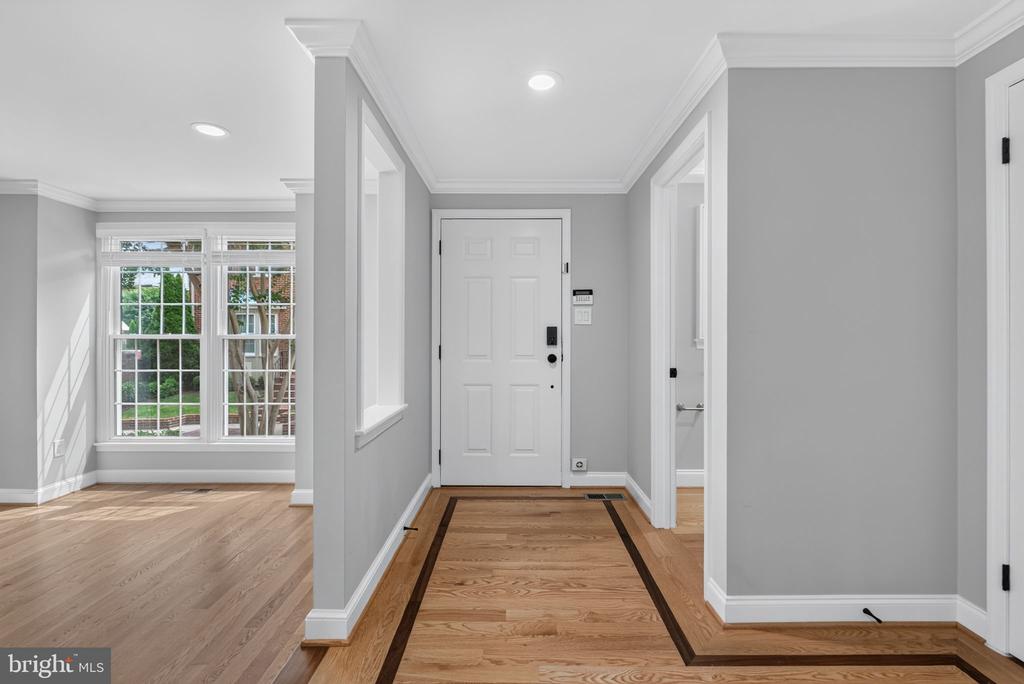Entry foyer with hardwood floors, dark inlaid borders, and large multi-pane windows beside the front door.