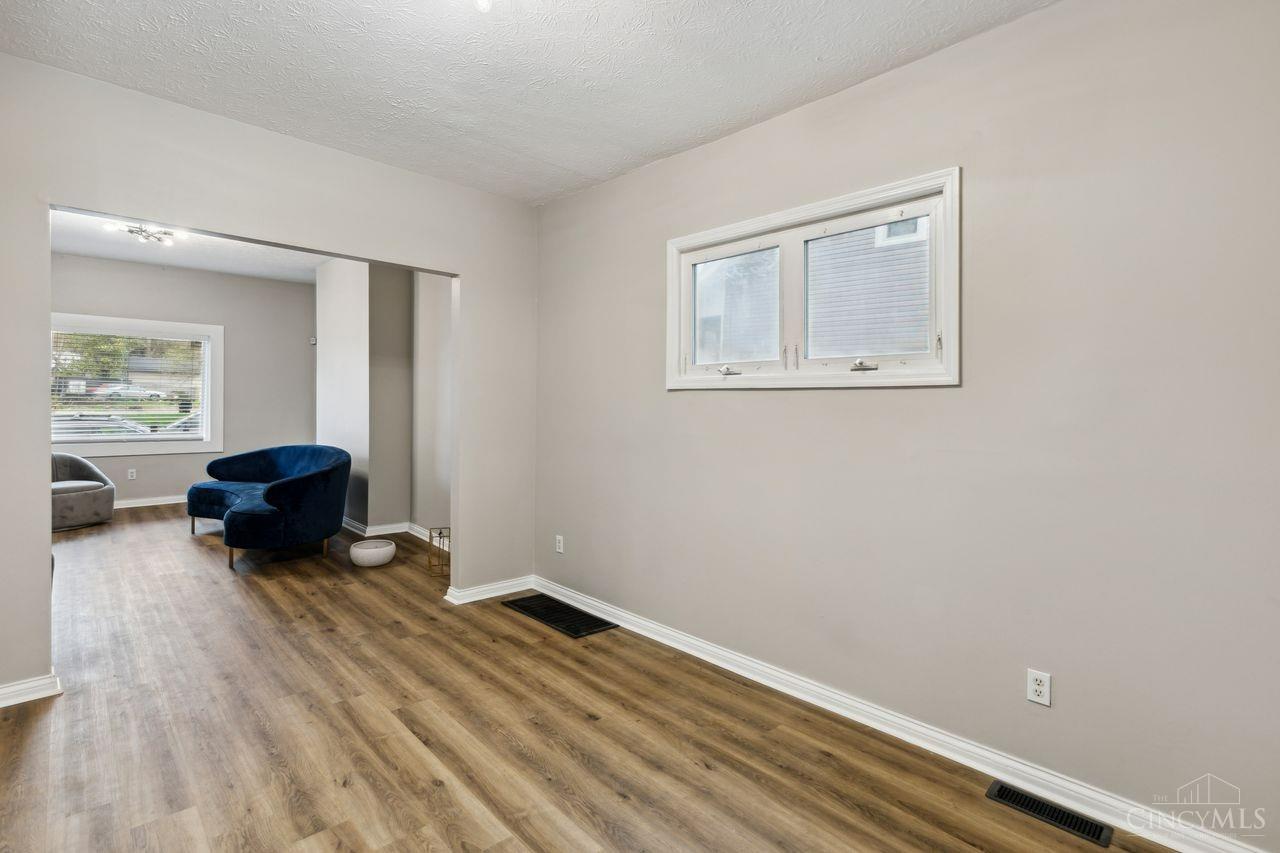 Living room with wood-look floors and a blue chair in the adjoining sitting area.